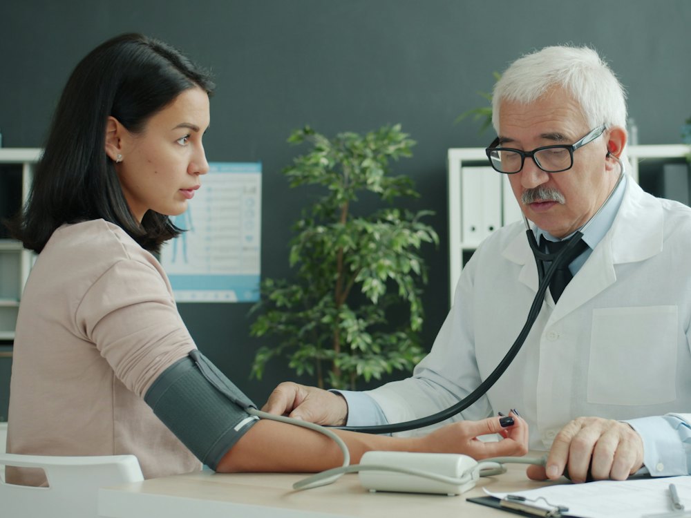 Medico del lavoro che misura la pressione a una lavoratrice